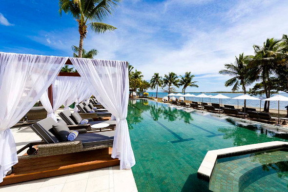 poolside day beds and pool with ocean in background